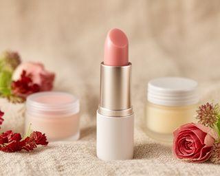 Lippenbalsam und kleine Pflegeverpackungen auf einem weichen, natürlichen Untergrund